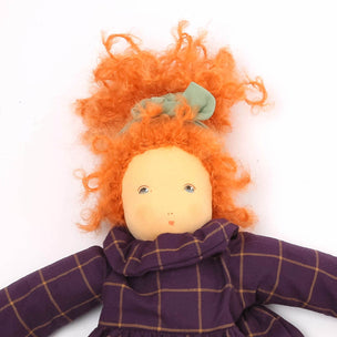 Toy doll with orange hair and a purple checkered dress on a white background