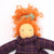 Toy doll with orange hair and a purple checkered dress on a white background