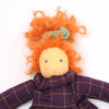 Toy doll with orange hair and a purple checkered dress on a white background