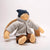Textile doll wearing a blue hat, gray coat, and brown pants on a white background