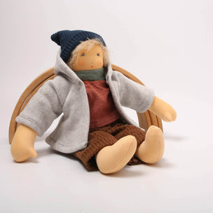 Textile doll wearing a gray coat, red shirt, brown pants, and blue hat on a white background