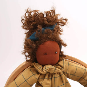 Textile doll with plaid coat and green pants on a white background