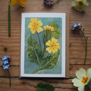 Card with floral design surrounded by real flowers on a wooden surface