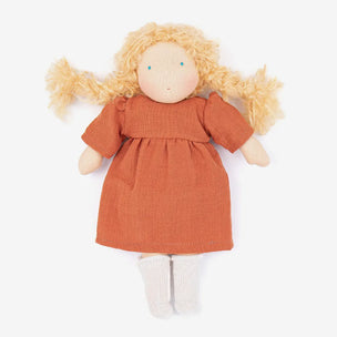 A handmade fabric doll with curly blonde yarn hair, a terracotta orange dress, and white socks, photographed against a clean white background.