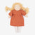 A handmade fabric doll with curly blonde yarn hair, a terracotta orange dress, and white socks, photographed against a clean white background.