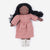 A handmade fabric doll with dark brown skin, long black curly hair, and a dusty pink dress, paired with white knit socks, shown against a plain white background.