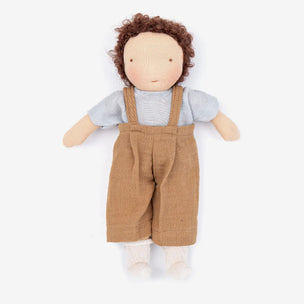 A handmade rag doll with curly brown hair, a beige face, a light blue-gray knit shirt, and brown corduroy overalls, laid flat on a white background.