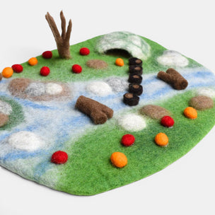 Felt play mat with animal figures and landscape elements on a white background