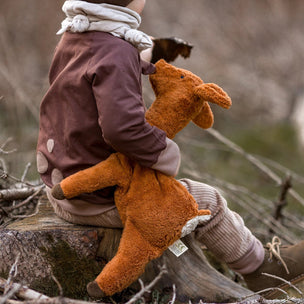 Child holding a stuffed animal in a natural setting