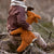 Child holding a stuffed animal in a natural setting