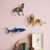 Decorative wall shelf with animal figurines and a framed picture on a pink wall.
