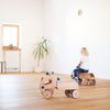 Child playing with wooden toy cars on a wooden floor.