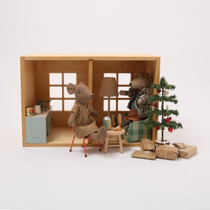 Miniature diorama with toy figures, furniture, and a Christmas tree inside a wooden box.