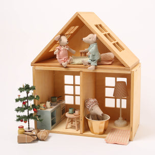 Wooden dollhouse with miniature furniture and decorative items on a white background