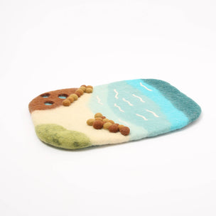 Colorful pet toy resembling a beach scene with sand, water, and rocks on a white background