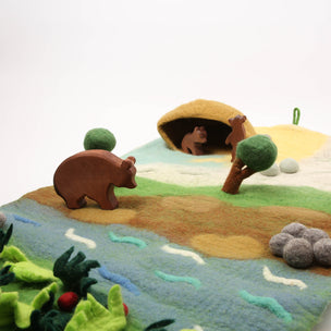 Felt play scene with bears and a cave on a white background