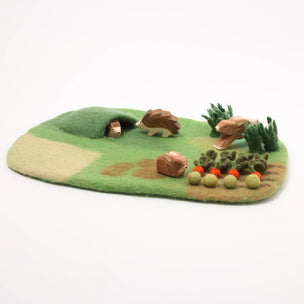 Felt playset with hedgehogs, rabbits, and vegetables on a green base.