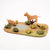 Model of two lions by a pond with plants on a beige background