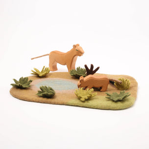 Wooden lion figurines on a naturalistic base with plants and water
