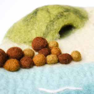 Felted toy with a green top and brown felt balls on a white background