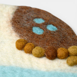 Close-up of a felted product with brown, green, and blue colors on a white background