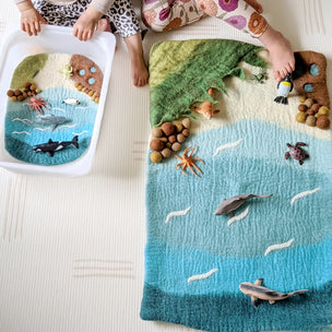 Children's play mat with ocean scene and toys on a light-colored surface