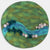 Round piece of felt with a landscape design featuring a frog, water, and rocks.