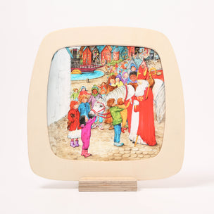 A square decorative Toverlux Window frame with rounded corners and a light wood base, featuring a colorful painted illustration of children and adults in a street scene. The plaque is displayed upright on a small wooden stand against a clean white background