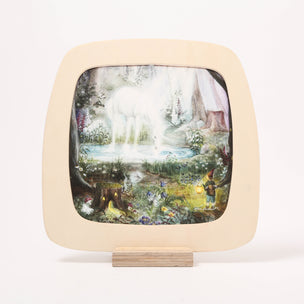 A toverlux window frame with rounded corner, featuring a hand-painted forest scene with a white horse and a small figure, mounted on a light wood stand against a white background.