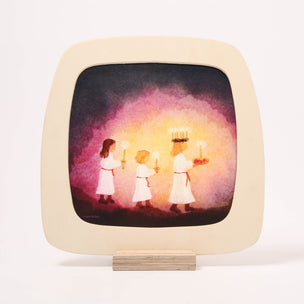 A square wooden toverlux frame with rounded corners, featuring a watercolor painting of three children in white robes holding candles, displayed on a small wooden stand against a white background