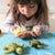 Child holding felted turtle toys on a blue blanket