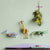 Decorative wall hooks shaped like a giraffe, lizard, and airplane on a light green wall.