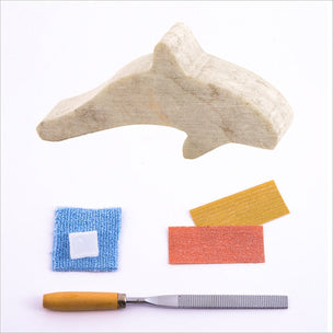 Contents of Studiostone Creative's soapstone orca making kit including: Sandpaper, wax, cloth, file and soapstone orca shape | Conscious Craft