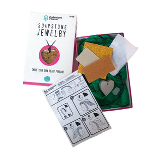 Contents of Studiostone Creative's soapstone heart pendant kit including: box, instruction sheet, sandpaper, wax, cloth, soapstone heart shape and black waxed string 