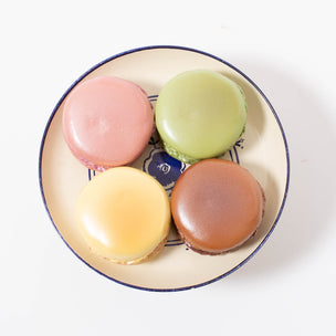 Four different coloured/flavoured resin macarons from Maileg on a hand painted cream metal cake stand with blue detailing | © Conscious Craft