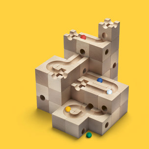 Wooden marble run construction using the Cuboro Standard 50 set showing marbles in motion and a yellow background | Conscious Craft